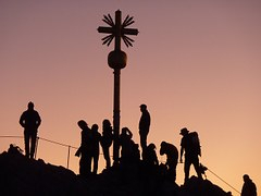 ein Kreuz auf einem Berg, darum herum Menschen