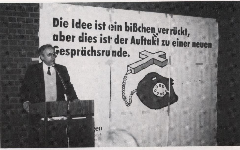 Zeitungsfoto von P. Euchar vor einem plakat mit dem Logo der Telefonseelsorge